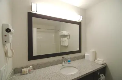 a bathroom with a sink and a large mirror at Paradise Inn and Suites Redwater in Redwater