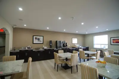 a dining room with tables and chairs and a kitchen at Paradise Inn and Suites Redwater in Redwater
