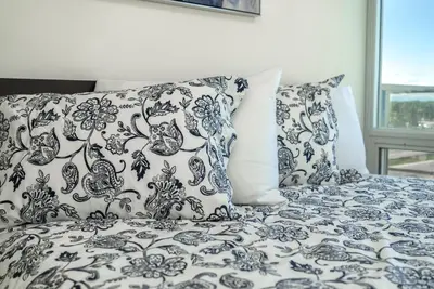 a bed with blue and white sheets and pillows at UC Stampede Condo by Train, Hospital, free UG parking & Gym, AC, full kitchen in Calgary