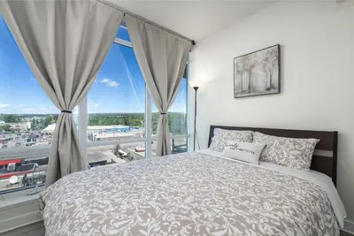 a bedroom with a bed and a large window at UC Stampede Condo by Train, Hospital, free UG parking & Gym, AC, full kitchen in Calgary