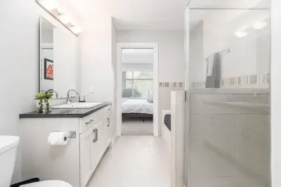 a white bathroom with a sink and a shower at Kelowna family-friendly lake & Mountain view Luxury condo with AC, pool, Hot tub, near winery and shopping center in West Kelowna
