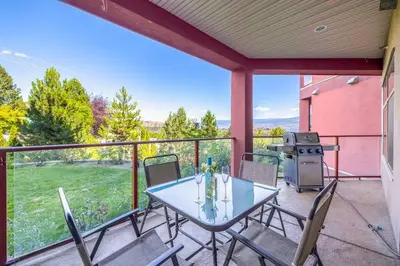 a patio with a table and chairs and a grill at Kelowna family-friendly lake & Mountain view Luxury condo with AC, pool, Hot tub, near winery and shopping center in West Kelowna
