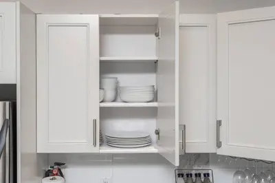 a kitchen with white cabinets with plates in them at Kelowna family-friendly lake & Mountain view Luxury condo with AC, pool, Hot tub, near winery and shopping center in West Kelowna