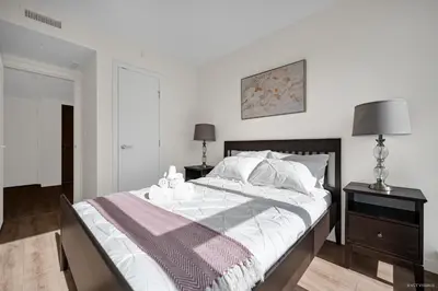 a white bedroom with a large bed with a night stand at Stylish and Tranquil Retreat in Richmond City Center in Richmond