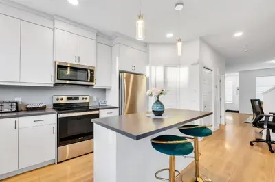 a kitchen with white cabinets and a kitchen island with green chairs at Your Happy Place Seton3 bed. Sleeps 6. 2.5bath in Calgary