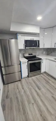 a kitchen with stainless steel appliances and white cabinets at Cozy One bedroom BSMT Apartment in Edmonton