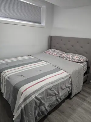 a bed sitting in a bedroom with a window at Cozy One bedroom BSMT Apartment in Edmonton