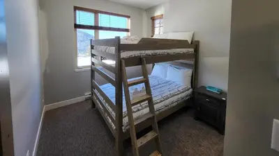 a bedroom with a bunk bed and a window at Powder Heights #22 townhouse in Sun Peaks