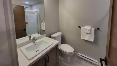 a white bathroom with a toilet and a sink at Powder Heights #22 townhouse in Sun Peaks