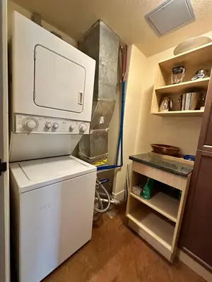 a small kitchen with a white refrigerator and a counter at Mountain Retreat Corner Suite -Pool - Hot Tub & Spa Escape in Canmore