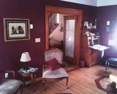 a living room with a chair and a table with a lamp at Phoenix House B&B in Stettler