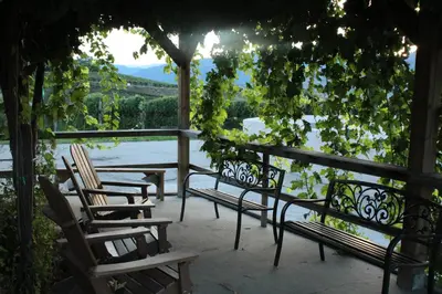 a group of chairs sitting on a patio overlooking a river at D'Angelo Winery Farm House in Penticton