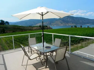 a table and chairs with an umbrella on a balcony at D'Angelo Winery Farm House in Penticton