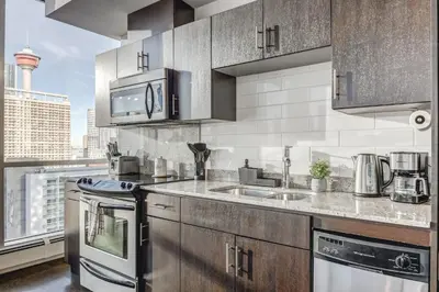 a kitchen with stainless steel appliances and a large window at Luxury 2BR Condo - Downtown City Views in Calgary