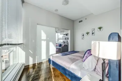 a white bedroom with a bed and a lamp at Luxury 2BR Condo - Downtown City Views in Calgary