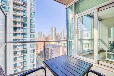 a balcony with a wooden table and chairs on it at Luxury 2BR Condo - Downtown City Views in Calgary