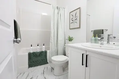 a white bathroom with a toilet and a sink at Stylish Retreat with King Bed, Long Stays, WEM, Disney+ in Edmonton