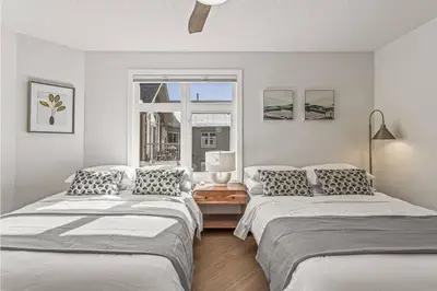 two beds in a white room with a window at W411 NEW- TOP of the World Canmore MTN Retreat in Canmore