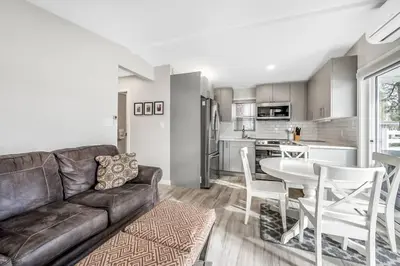a living room with a couch and a table and a kitchen at Family-friendly Cottage with amazing views in West Kelowna