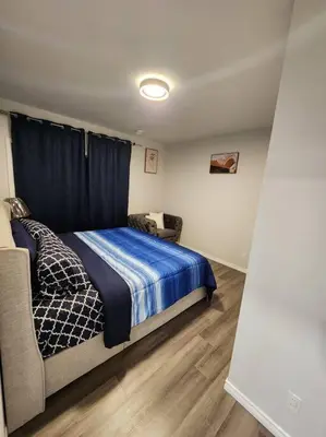 a bedroom with a bed with a blue blanket and a chair at Cozy one bedroom in Airdrie in Airdrie