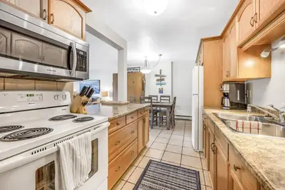 a kitchen with a white stove top oven next to a counter at The Lakeside Condo #202 in West Kelowna