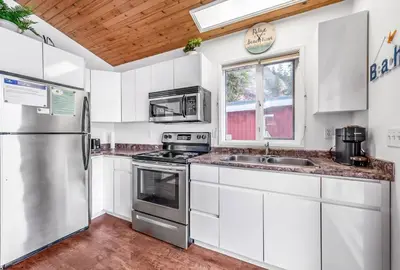 a kitchen with white cabinets and stainless steel appliances at Beautiful Cabin Right next to Lake Okanagan #5 in West Kelowna
