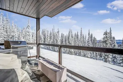 a balcony with a grill and snow covered trees at Inuksuk Lodge - 4800 sq ft of Big White Excellence! in Big White