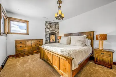a bedroom with a large bed and a fireplace at Inuksuk Lodge - 4800 sq ft of Big White Excellence! in Big White
