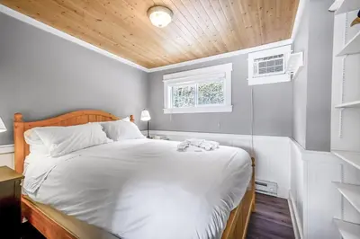 a bedroom with a white bed with a wooden headboard at Lakeside Serenity Retreat #10 in West Kelowna