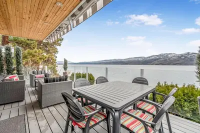 a patio with a table and chairs and a view of the water at Lakeside Serenity Retreat #10 in West Kelowna