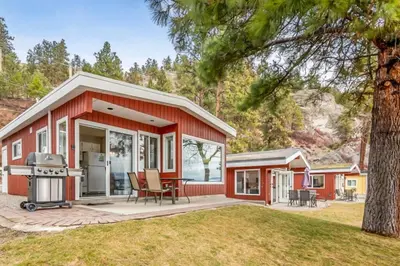a red house with a grill in a yard at The Perfect Getaway Cabin in the Okanagan #6 in West Kelowna