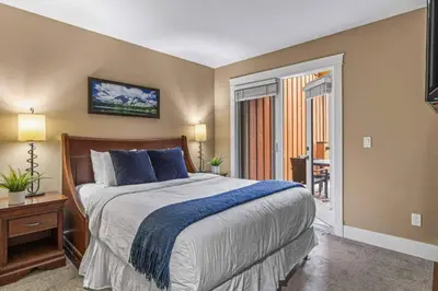 a bedroom with a large bed and a balcony at Gorgeous Mountain Condo - Hot Tub & Pool managed by Little Sister Getaways in Canmore