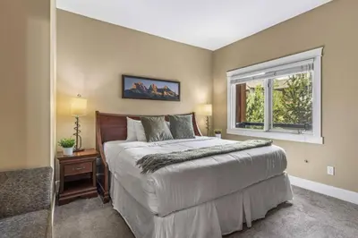 a bedroom with a large bed and a window at Gorgeous Mountain Condo - Hot Tub & Pool managed by Little Sister Getaways in Canmore