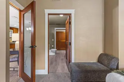 a living room with a chair and a bathroom at Gorgeous Mountain Condo - Hot Tub & Pool managed by Little Sister Getaways in Canmore