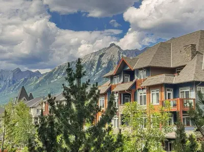 a large house with mountains in the background at Gorgeous Mountain Condo - Hot Tub & Pool managed by Little Sister Getaways in Canmore