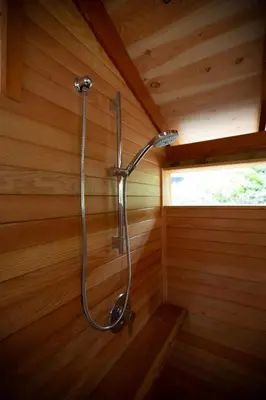 a shower in a cabin with a wooden wall at Sungate on Salt Spring - Luxurious Suite with Cedar Hot Tub & View in Salt Spring Island