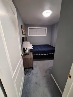 a small room with a bed and a lamp at 1-Bedroom Basement Suite in Yellowknife