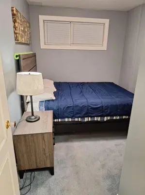 a bedroom with a bed and a table with a lamp at 1-Bedroom Basement Suite in Yellowknife