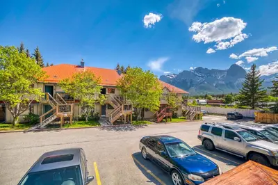 two cars parked in a parking lot in front of a house at Bow Valley Chalets-Entire 2 King Bedrooms townhouse in Canmore