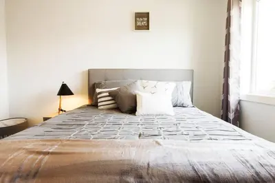 a bedroom with a large bed with a gray headboard at Modern Home - King Bed - Garage - Long Stays in Edmonton