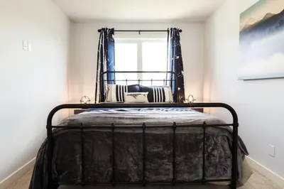 a black bed in a room with a window at Modern Home - King Bed - Garage - Long Stays in Edmonton