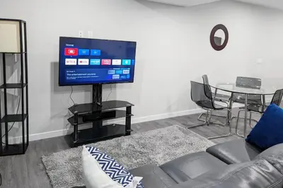 a living room with a couch and a tv and a table at The Fruitful Vineyard- A Beautiful 2 Bed Suite in Calgary