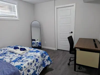 a bedroom with a bed and a desk and a mirror at The Fruitful Vineyard- A Beautiful 2 Bed Suite in Calgary