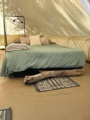 a bed in a tent with a log on the floor at #Y3 Willow Tree Yurt in Drumheller
