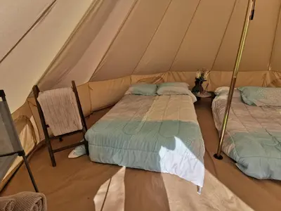 two beds in a tent with a chair at #Y4 Aurora Haven Yurt in Drumheller