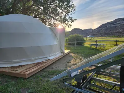 a tent sitting on the grass with the sunset in the background at #Y4 Aurora Haven Yurt in Drumheller