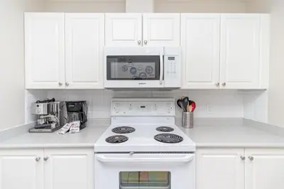 a white kitchen with a stove and a microwave at Harbour Retreat in Victoria