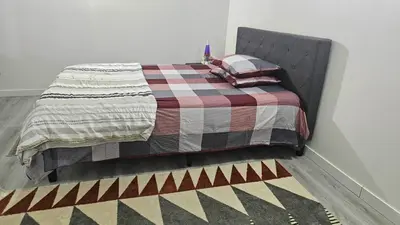 a bed with a checkered blanket and pillows on it at Bright and Cozy Room with Free Parking in Edmonton