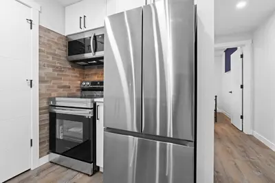a stainless steel refrigerator in a kitchen with white cabinets at Stylish Suite-NearWEM-4 Bed-Central in Edmonton