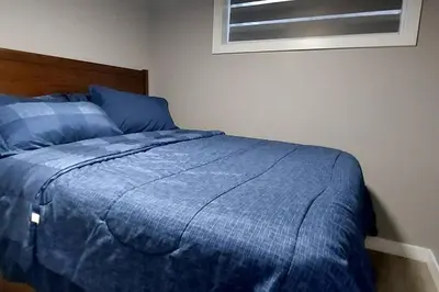 a bed with a blue comforter in a bedroom at Cozy 2-Bedroom Basement Guest Suite with Private Entrance and Proximity to the Airport in Edmonton